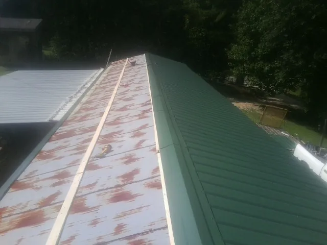 Old rusted panels beside newly installed green metal roofing — Wind Damage Roof Repair by Roofing Brothers in Nolensville
