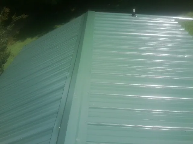New green metal panels meeting at the ridge of a roof — Flat Roof Repair work by our crew in Nolensville