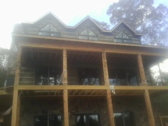 Dormers and porch framing on a large log home under construction — Roof Coating work by our crew in Nolensville