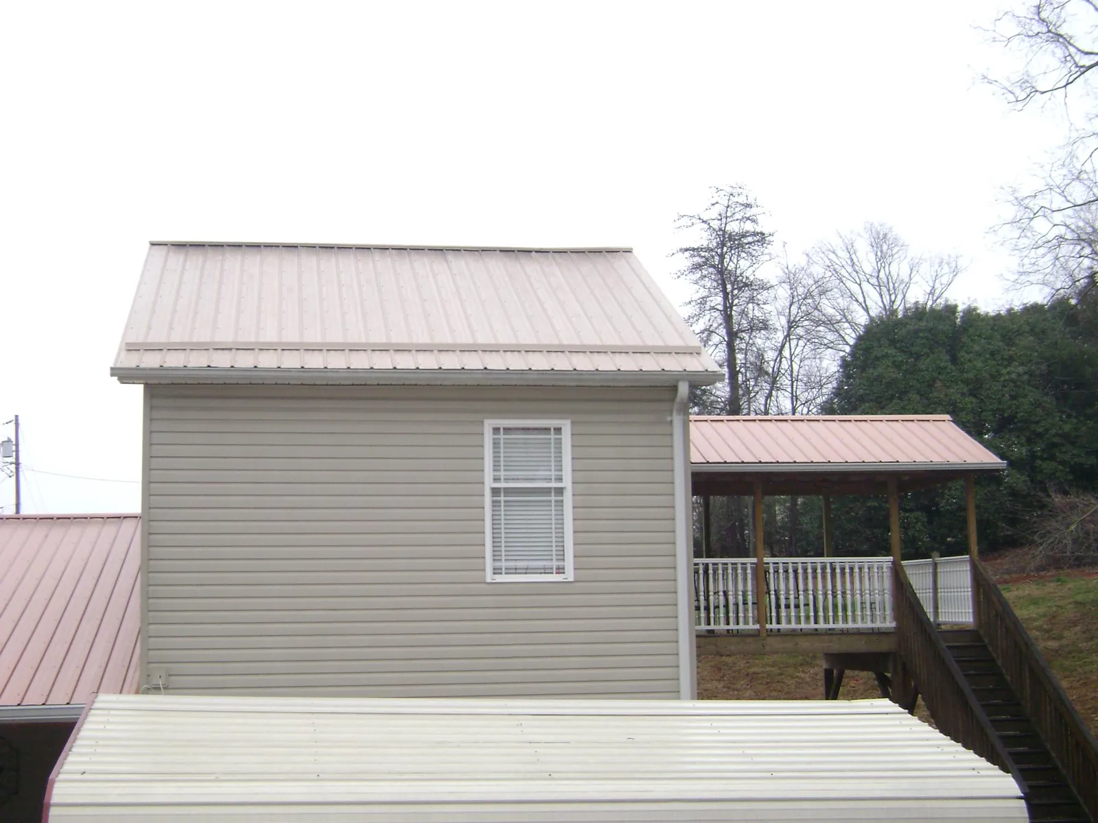 Tan metal roofs on a two story addition and attached porch, from a Roof Replacement job in Nolensville