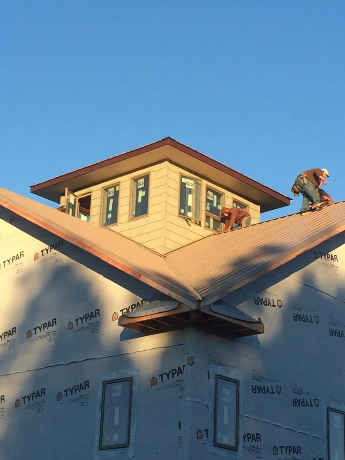 Roofers working around a rooftop cupola on a new metal roof at sunset — Roof Waterproofing in Nolensville by Roofing Brothers